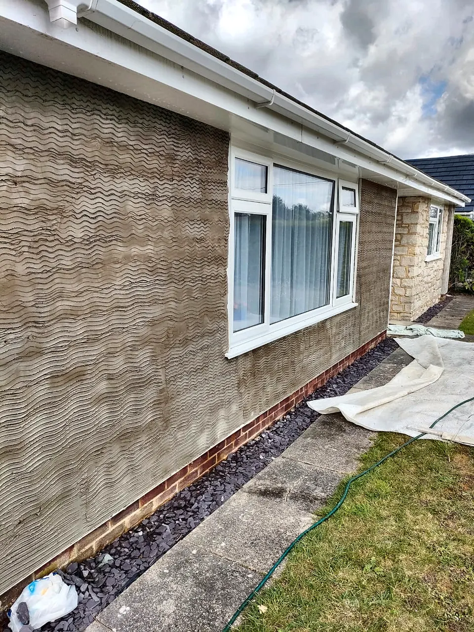 Scratch coat of render on the side wall of a bungalow before the finish coat
