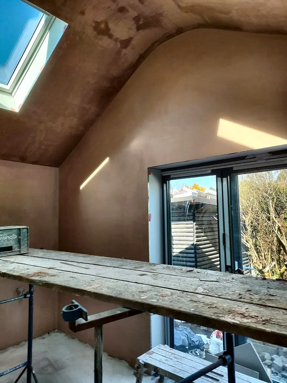 Plastered vaulted ceiling and walls with roof windows and a patio door