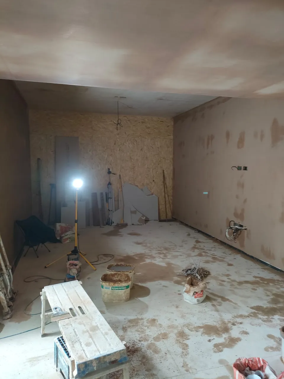 Large room with skimmed walls and ceiling drying, a work light and a platform in the foreground