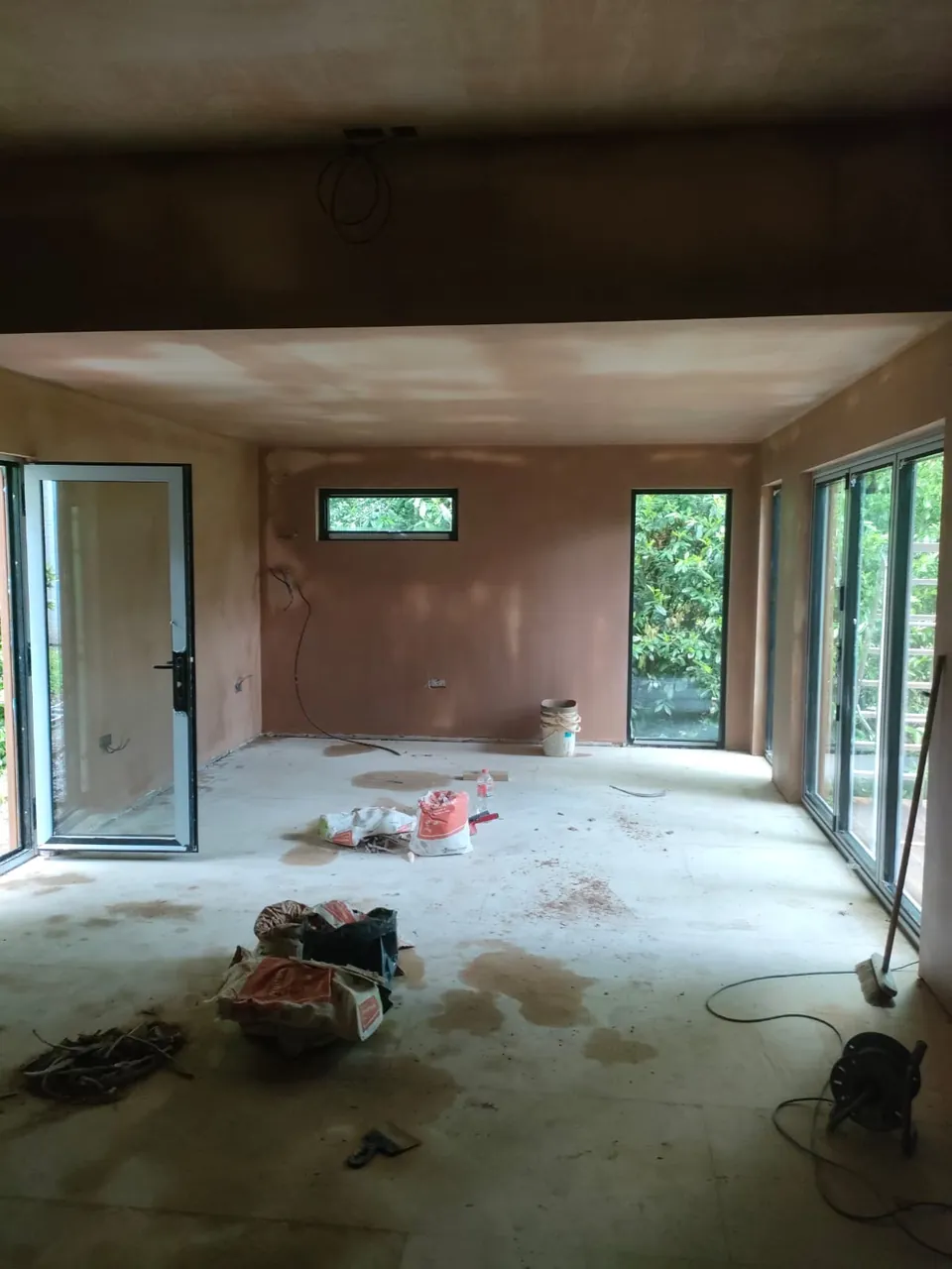 Skimmed walls and ceiling in a room with bifold doors, windows and a door open to the garden