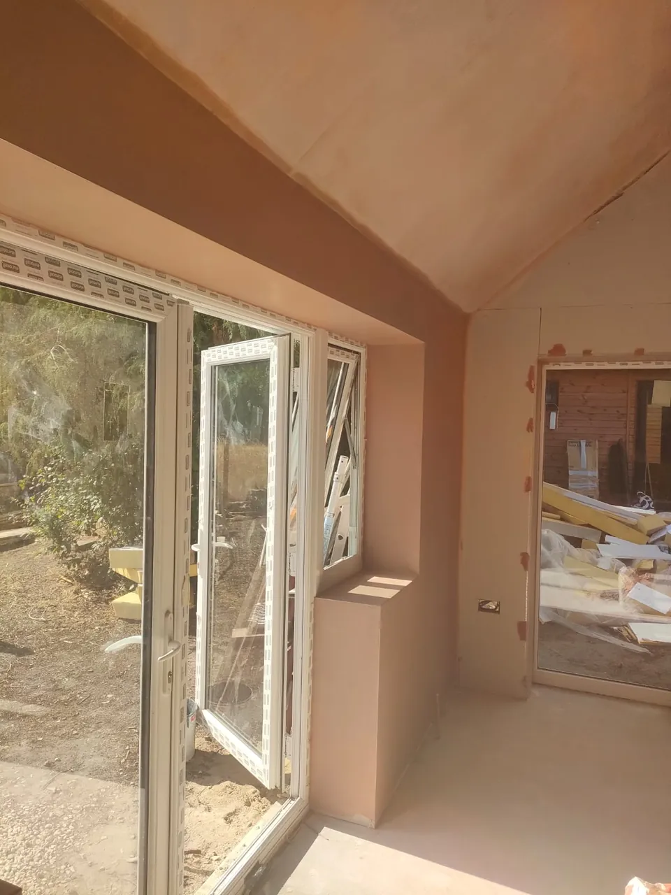 Finished plaster on a vaulted ceiling and walls around white patio doors