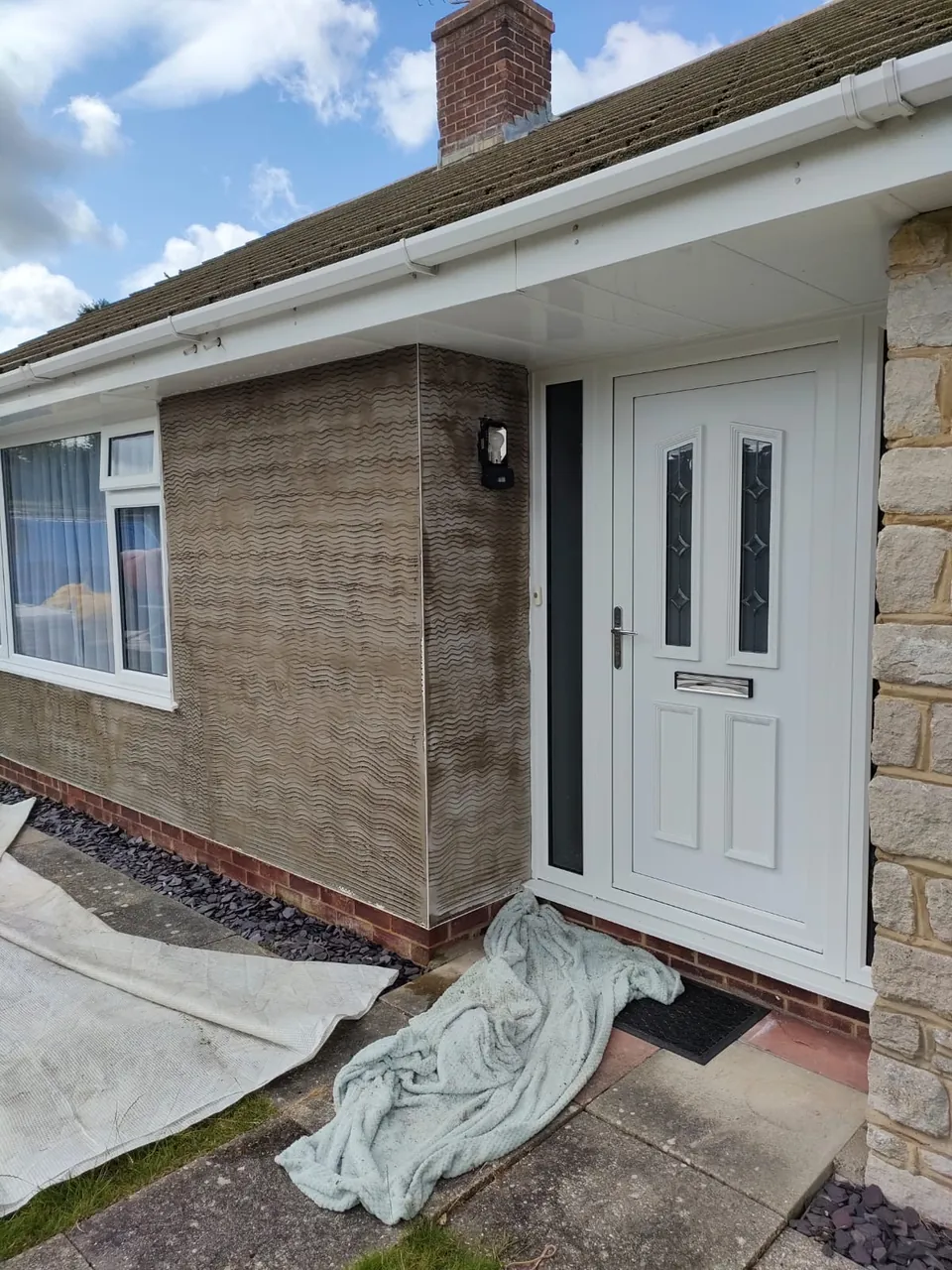 Scratch coat of render on the wall beside the front porch of a bungalow with a stone clad pier
