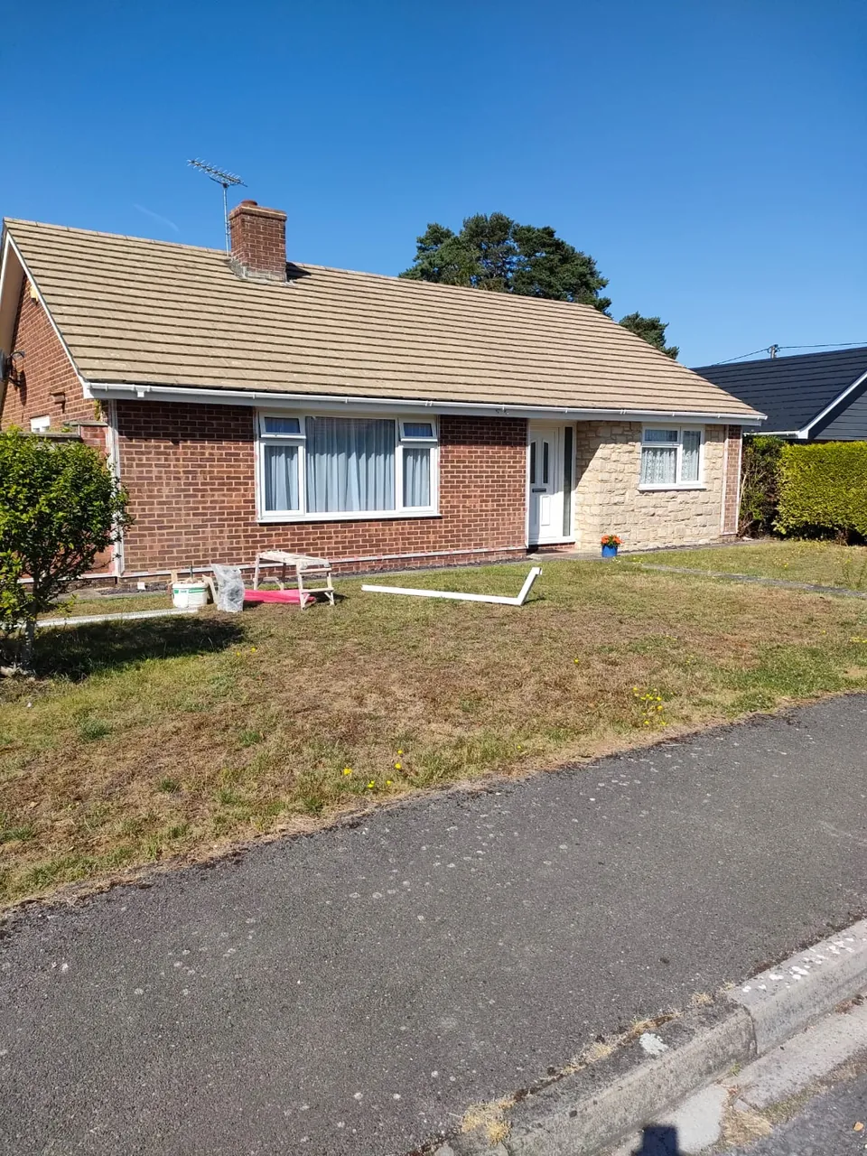 Front of a brick bungalow with a stone clad porch before the render was applied