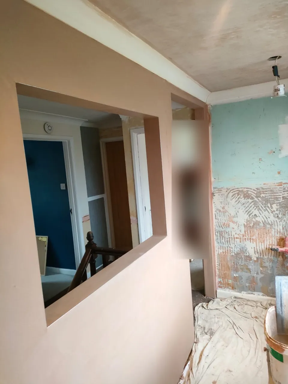 Smooth newly plastered landing wall around an opening to the stairs, with the old wall still to be done on the right